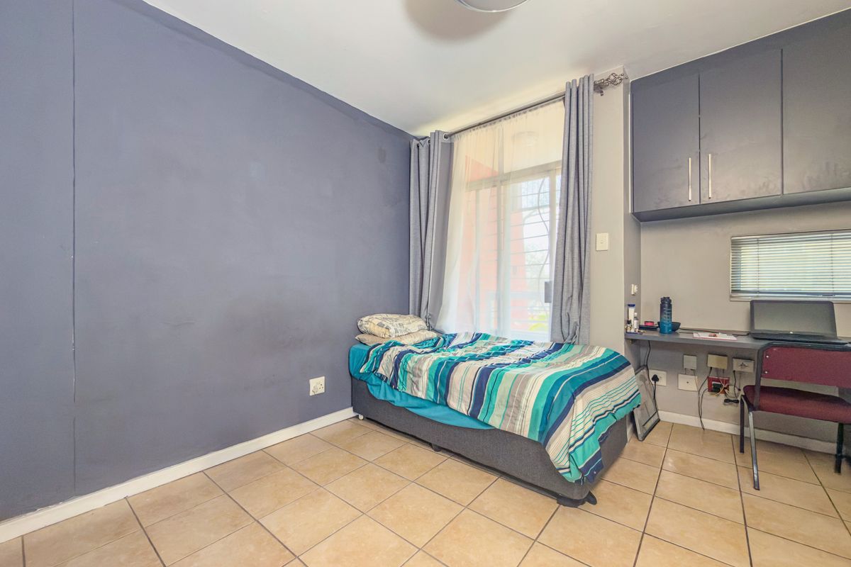 A bedroom featuring tiled flooring, a built-in desk area with overhead cabinetry, and a sliding glass door providing access to the exterior.