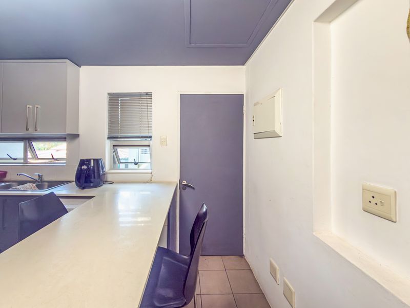 A functional kitchen area featuring built-in cabinetry, a clean countertop, tiled flooring, and a recessed wall niche, providing a practical workspace.