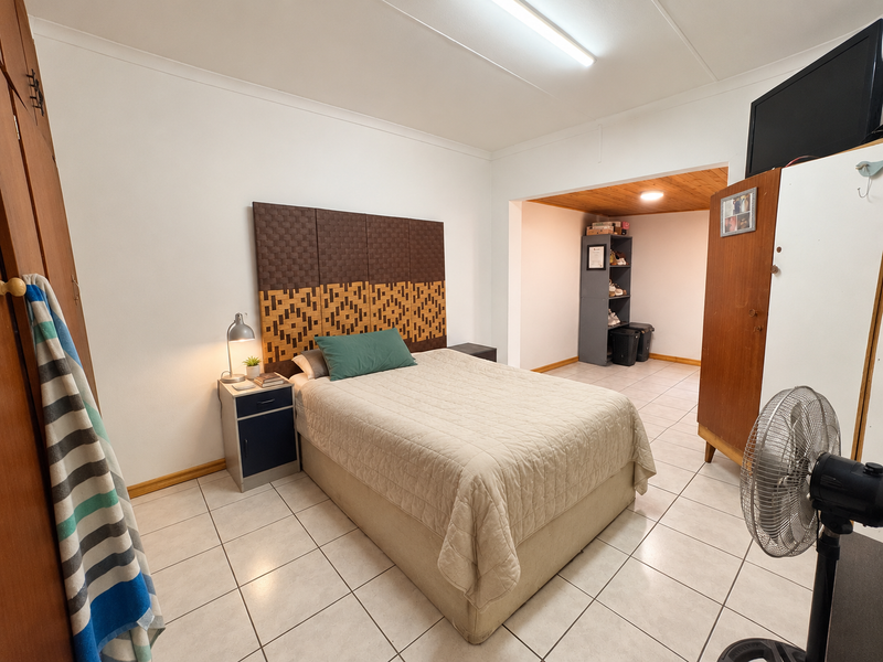 A bedroom featuring tiled flooring, built-in cupboards, and an adjoining alcove area with wood-paneled ceiling detail.