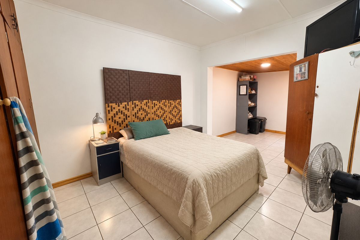 A bedroom featuring tiled flooring, built-in cupboards, and an adjoining alcove area with wood-paneled ceiling detail.