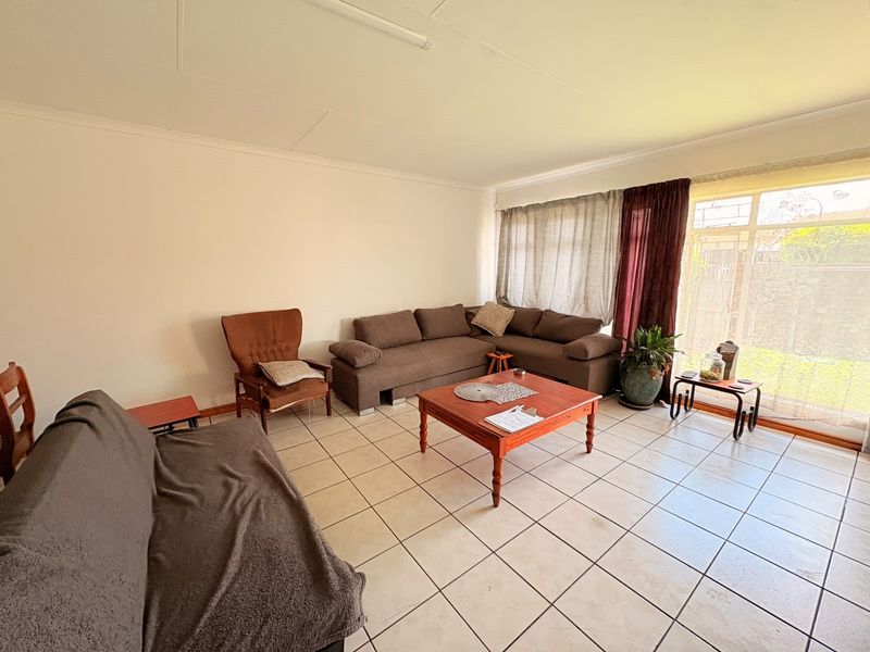 A spacious living room featuring ceramic floor tiles and a large sliding glass door providing access to the outdoor area.