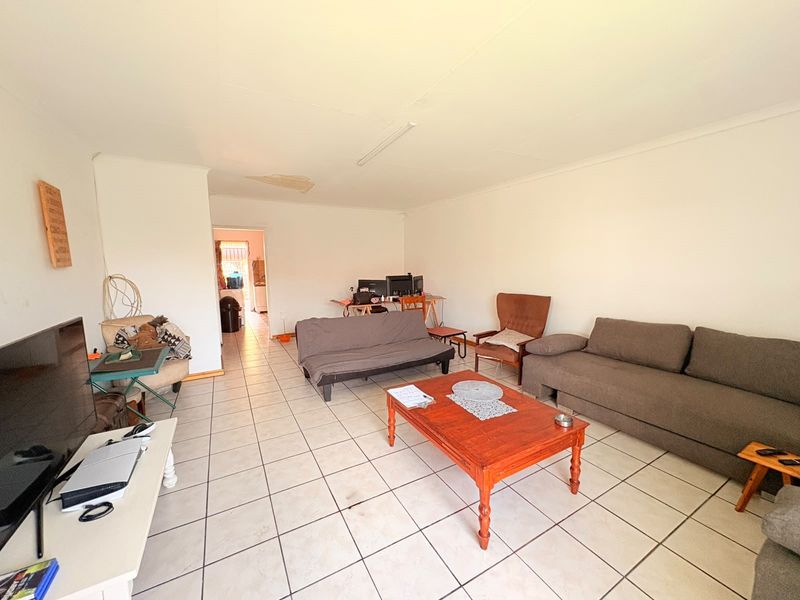Spacious living area featuring tiled flooring and coved ceilings, requiring some maintenance to address ceiling damage and floor tile repairs.