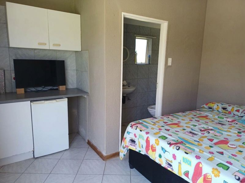 Open-plan studio space featuring a kitchenette with built-in cabinetry and an adjoining bathroom with tiled finishes.