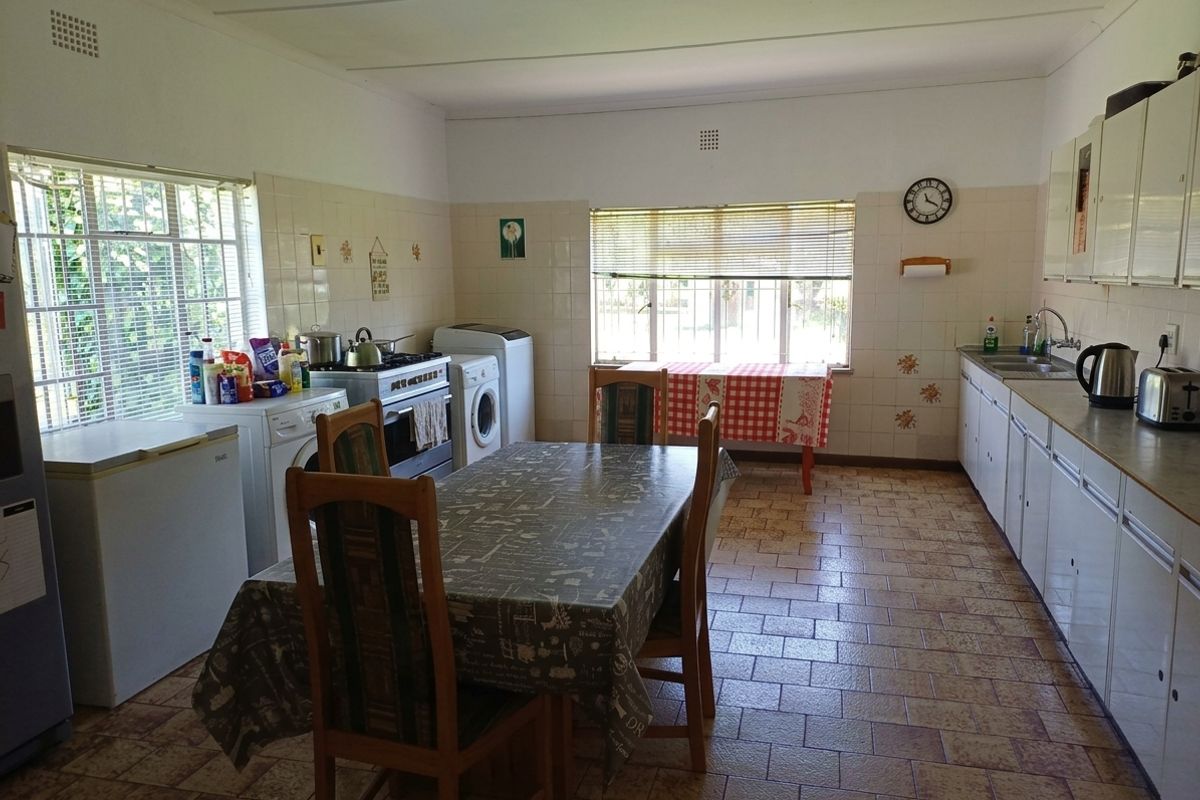 Spacious kitchen featuring tiled flooring, extensive built-in cabinetry, laminate countertops, and a functional layout with integrated laundry appliance connections.
