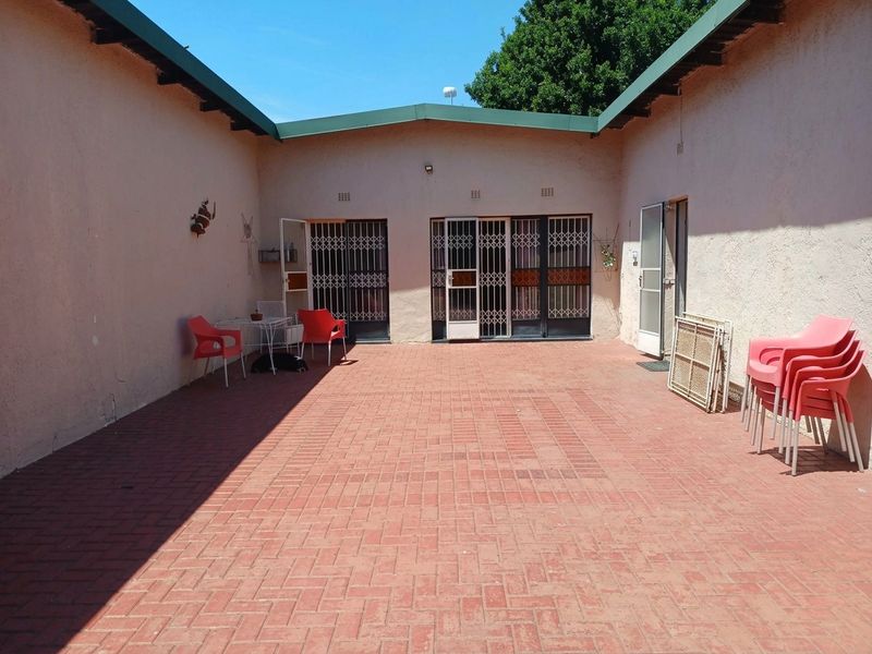 A paved outdoor courtyard area featuring brick flooring, security gates, and access to the main dwelling, offering a functional space for outdoor living.