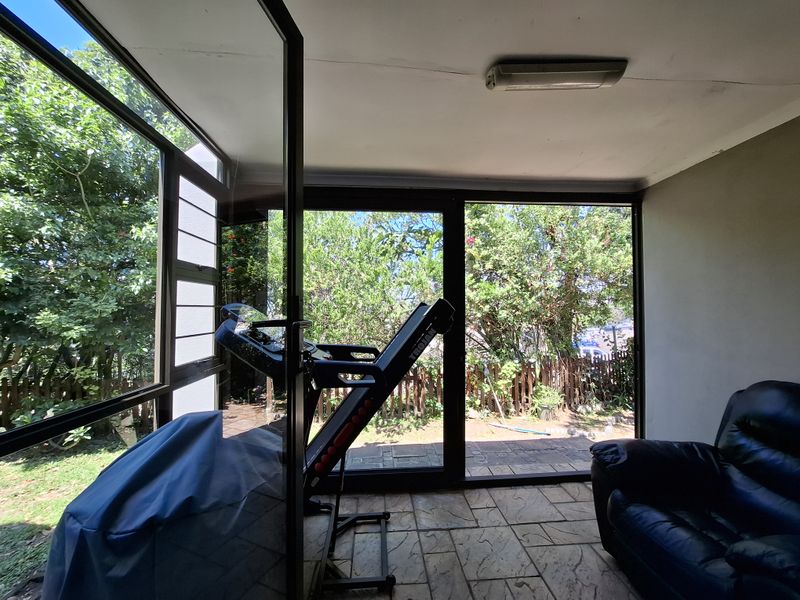 Enclosed patio area featuring large glass sliding doors, tiled flooring, and direct access to the garden, offering a bright and versatile space.