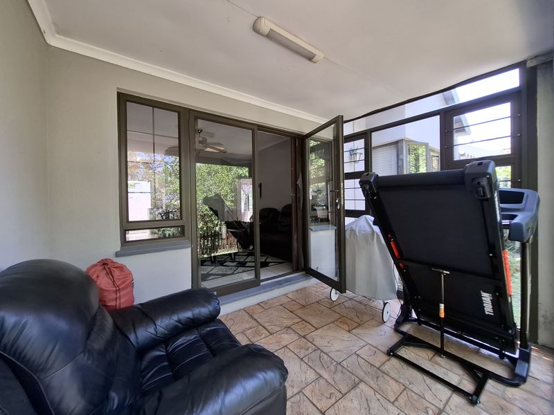 A covered patio area featuring tiled flooring, aluminium-framed windows, and sliding glass doors providing access to the interior living space.
