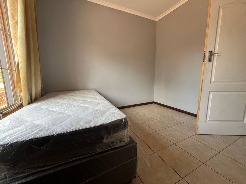 A simple, neutrally painted bedroom featuring tiled flooring and a standard panel door, offering a clean and versatile space ready for personalization.