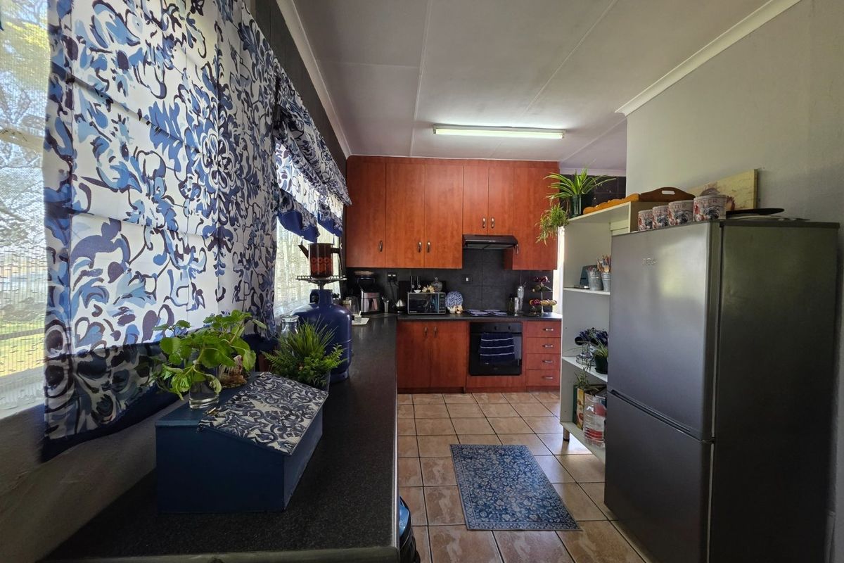 A functional kitchen featuring wood-tone cabinetry, dark laminate countertops, built-in oven, extractor fan, and tiled flooring.