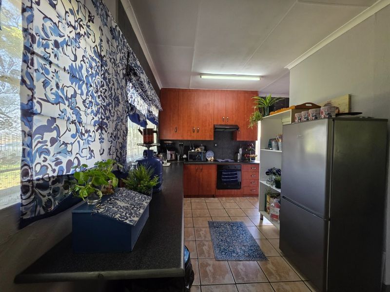 A functional kitchen featuring wood-tone cabinetry, dark laminate countertops, built-in oven, extractor fan, and tiled flooring.