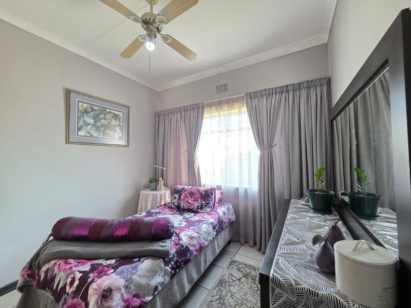 A functional bedroom featuring tiled flooring, a ceiling fan, and neutral wall finishes, providing a comfortable and well-maintained living space.