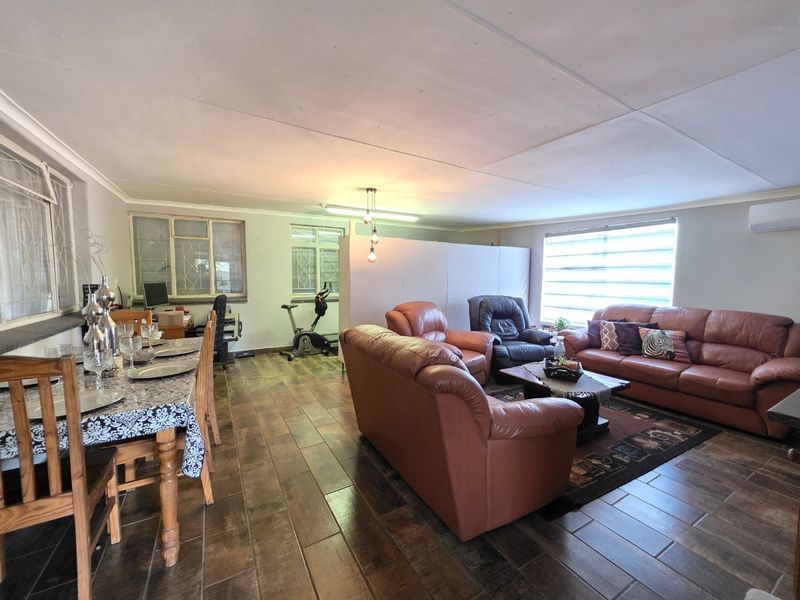 Spacious open-plan living and dining area featuring tiled flooring, split system air conditioning, and large windows with security bars.