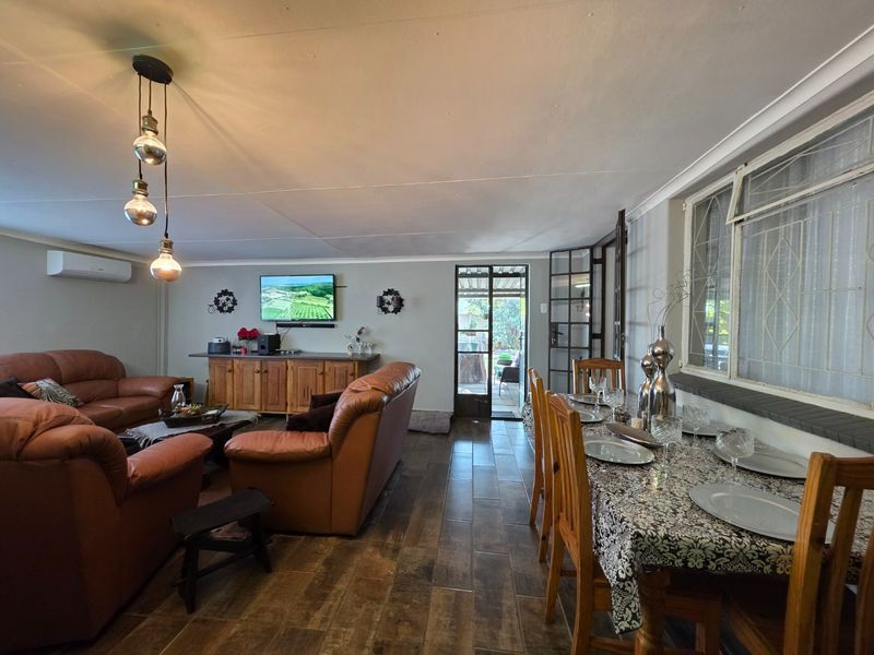 Spacious open-plan living and dining area featuring tiled flooring, modern pendant lighting, and direct access to the outdoor patio through a steel-framed door.
