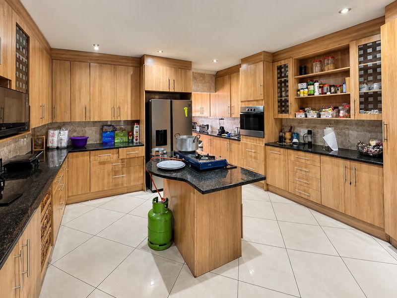 Spacious kitchen featuring extensive wooden cabinetry, granite countertops, built-in oven, and tiled flooring, offering ample storage and workspace for culinary activities.