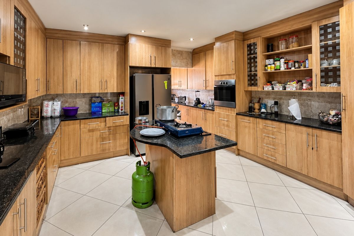 Spacious kitchen featuring extensive wooden cabinetry, granite countertops, built-in oven, and tiled flooring, offering ample storage and workspace for culinary activities.