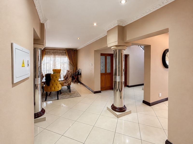 Spacious hallway featuring tiled flooring, decorative columns, and recessed lighting, providing an open transition between the living areas and other rooms of the home.