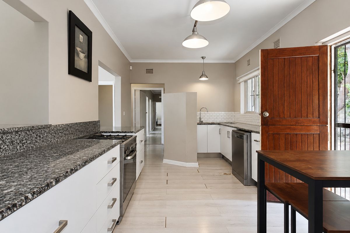 A functional kitchen featuring granite countertops, a gas hob, built-in oven, and subway tile backsplash, with direct access to an outdoor area.