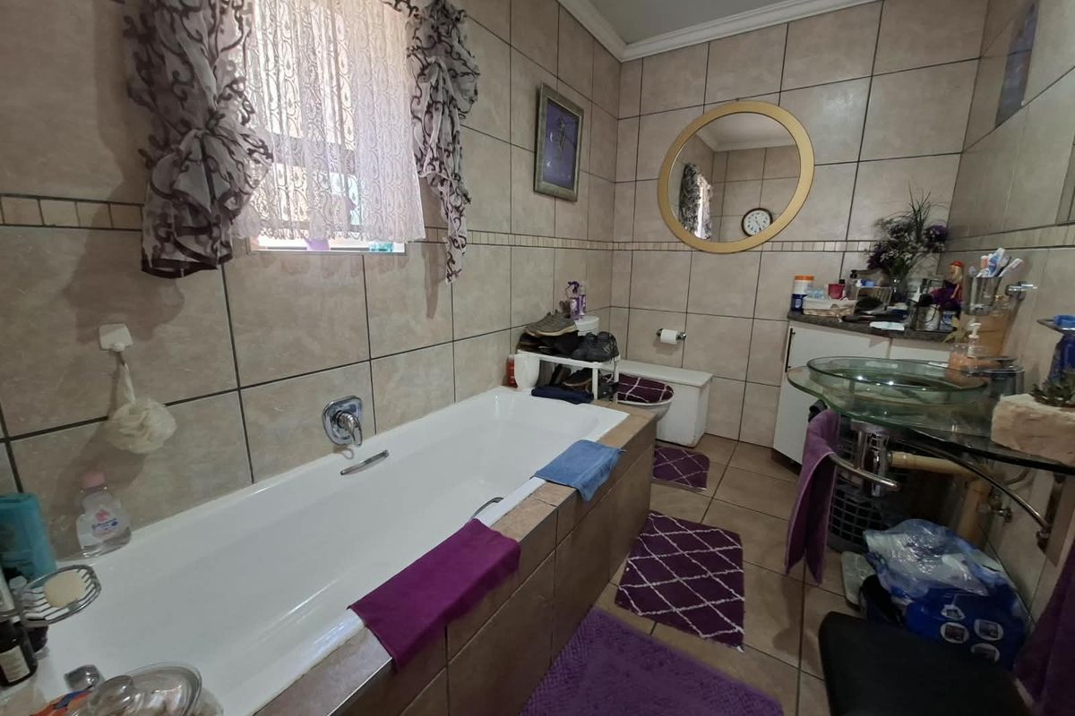 A functional bathroom featuring a built-in bathtub, tiled wall finishes, a glass vessel sink, and a toilet, offering a practical layout for daily use.