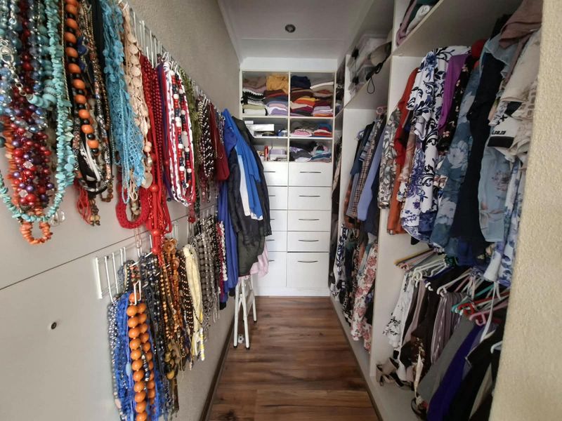 A functional walk-in closet featuring extensive built-in cabinetry, integrated drawer storage, and laminate flooring, providing efficient organization and storage space.