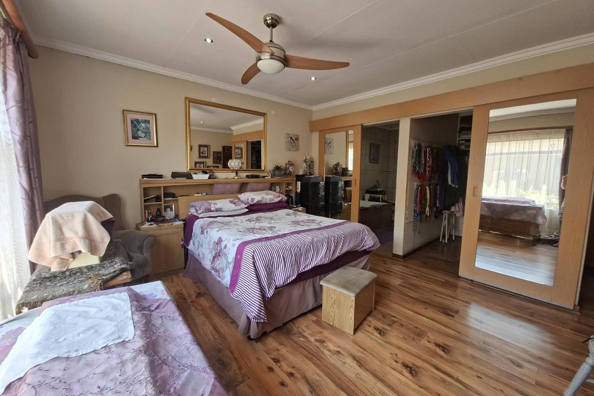 Spacious bedroom featuring laminate flooring, recessed lighting, a ceiling fan, and built-in wardrobes with mirrored sliding doors.