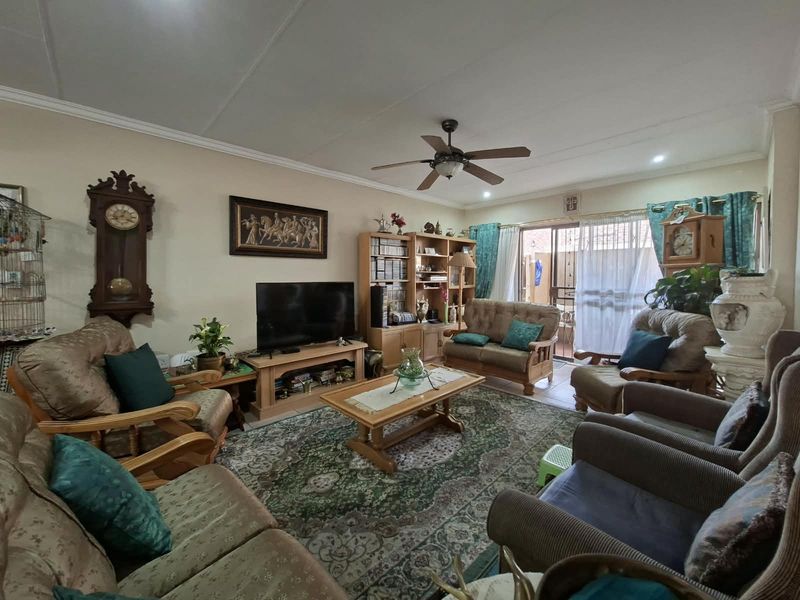 A spacious living room featuring a ceiling fan, tiled flooring, and a sliding glass door providing access to the outdoor area.