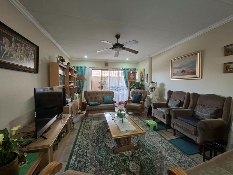 A comfortable living room featuring tiled flooring, a ceiling fan, and a sliding glass door providing access to the outdoor area.
