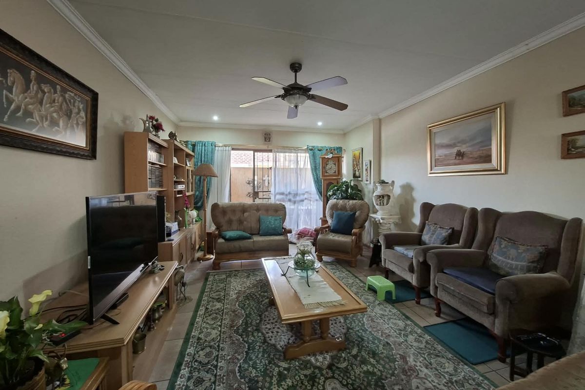 A comfortable living room featuring tiled flooring, a ceiling fan, and a sliding glass door providing access to the outdoor area.