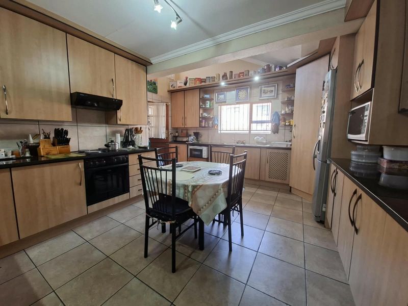 A functional kitchen featuring laminate cabinetry, built-in oven, extractor fan, and tiled flooring, offering ample storage and workspace for daily meal preparation.