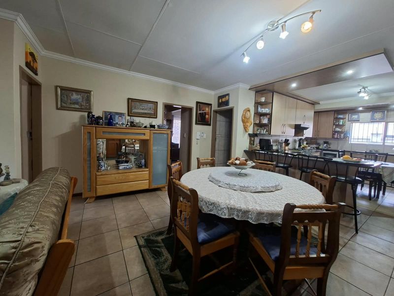 Open-plan living and dining area featuring tiled floors, coved ceilings, and a functional kitchen with a breakfast bar and built-in cabinetry.