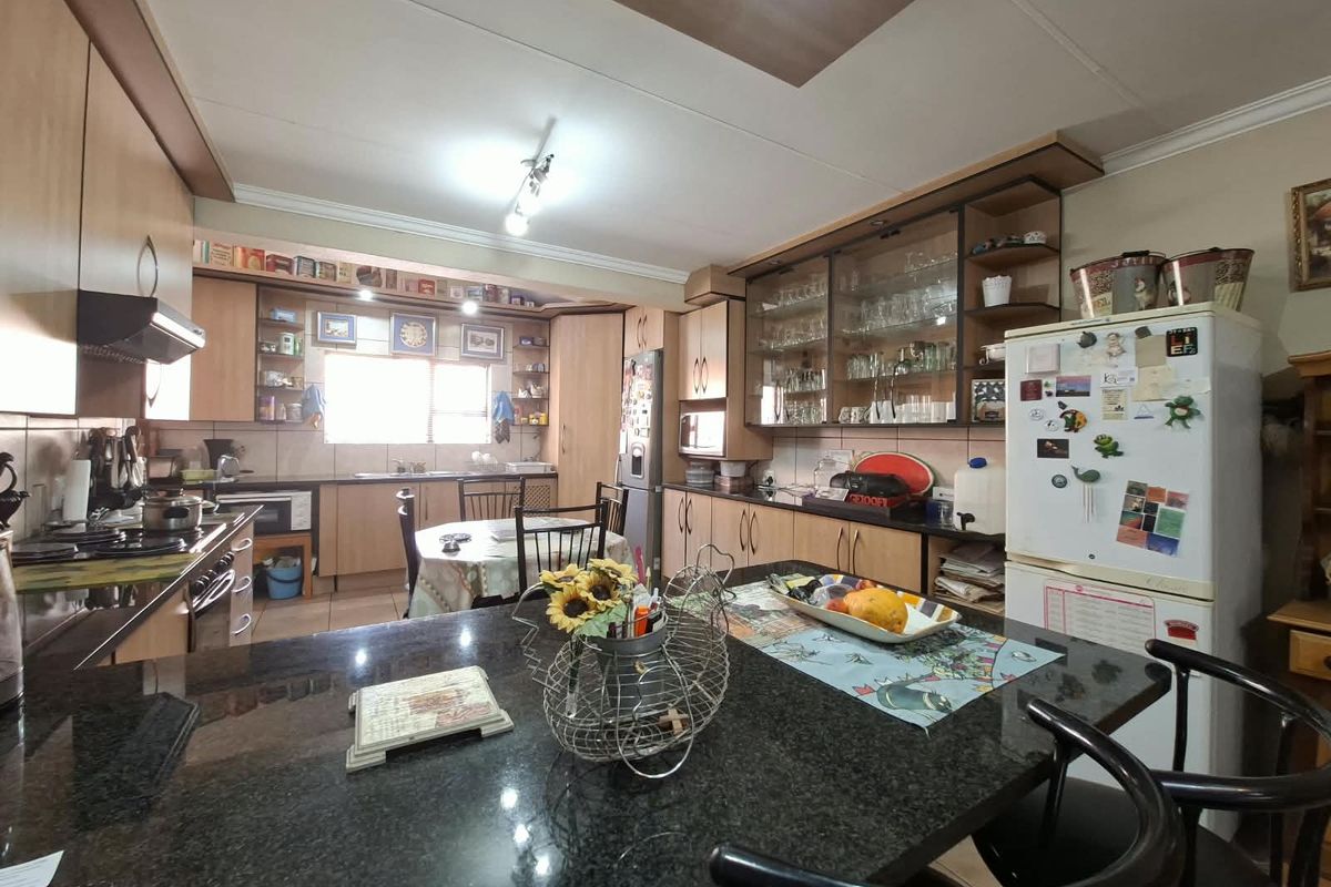 Spacious kitchen featuring granite countertops, extensive laminate cabinetry, glass-front display units, and a functional layout with integrated appliances.
