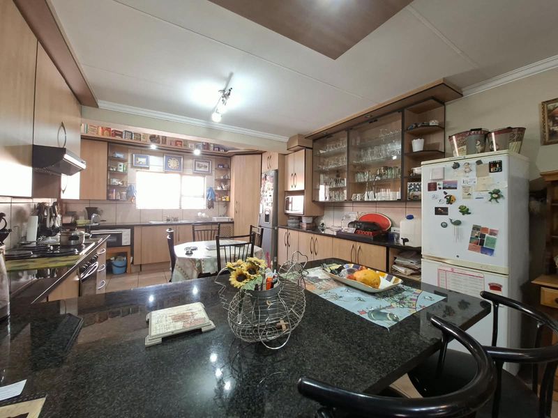 Spacious kitchen featuring granite countertops, extensive laminate cabinetry, glass-front display units, and a functional layout with integrated appliances.