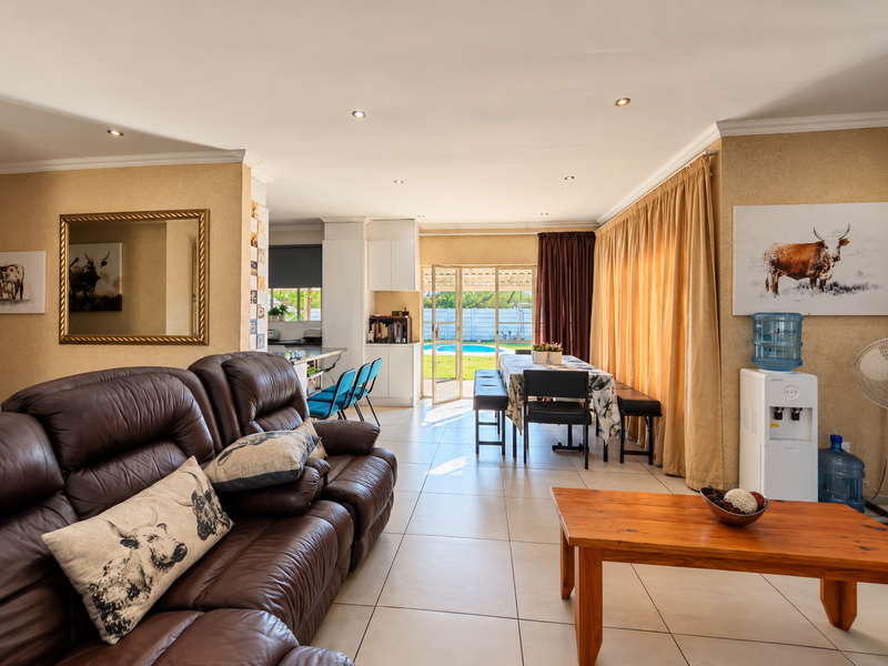 Spacious open-plan living and dining area featuring tiled floors, recessed lighting, and direct access to the outdoor patio and pool area.