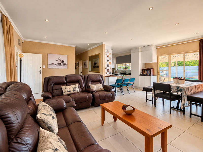 Spacious open-plan living and dining area featuring tiled floors, recessed lighting, and seamless access to the outdoor patio through sliding glass doors.