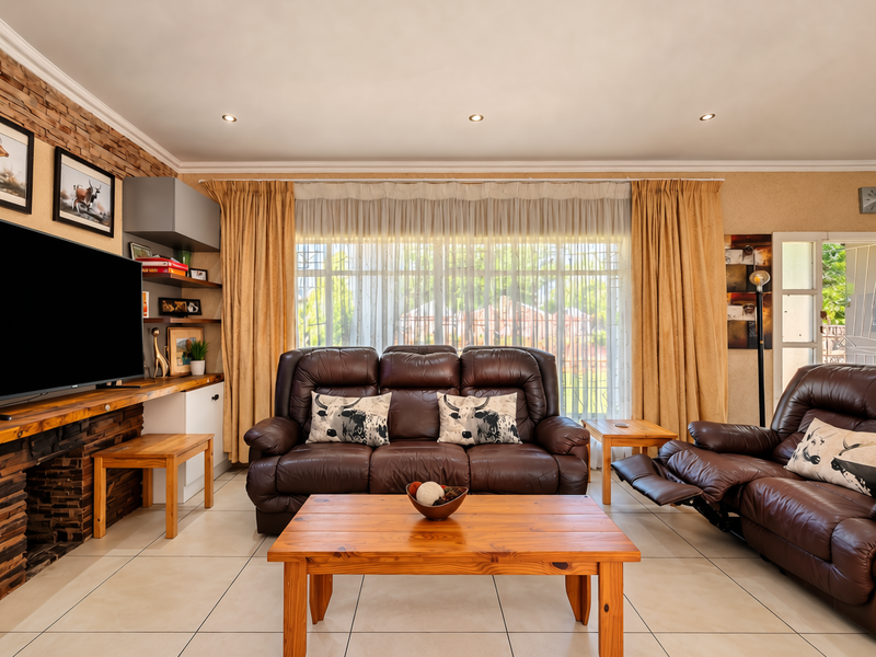 A comfortable living room featuring a stone accent wall, built-in shelving, tiled flooring, and large windows with natural light.