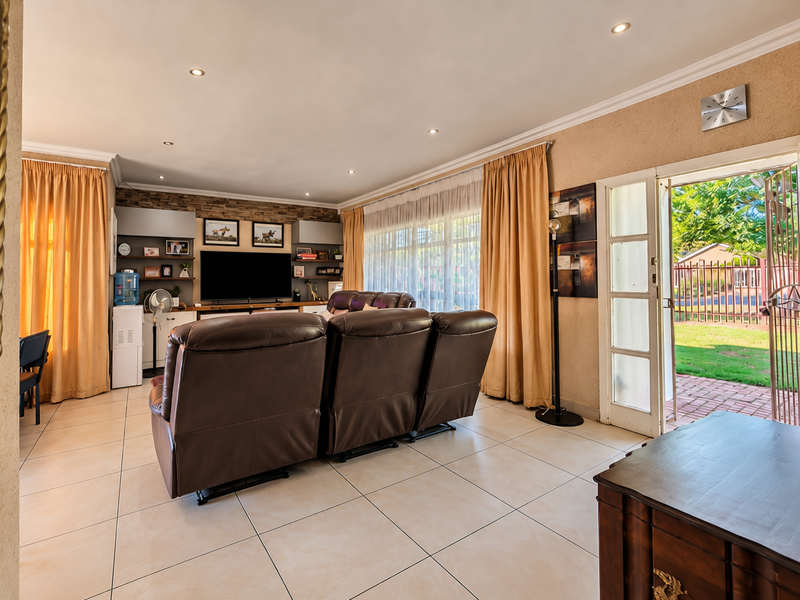Spacious living room featuring tiled flooring, recessed downlights, and built-in shelving, with direct access to the outdoor patio area through a sliding glass door.