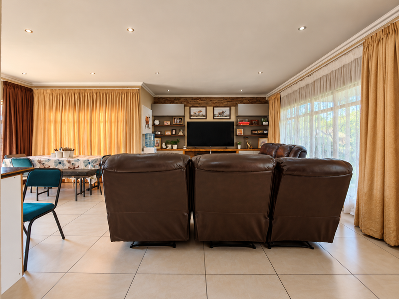 Spacious open-plan living and dining area featuring tiled floors, recessed lighting, and a custom built-in media unit with stone feature wall detailing.