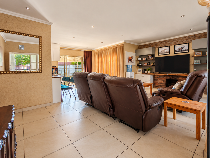 Spacious living room featuring tiled flooring, recessed downlighting, and a prominent stone feature wall with integrated shelving and cabinetry.