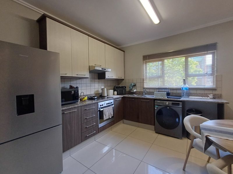 A functional kitchen featuring two-tone cabinetry, tiled backsplash, integrated oven with extractor fan, and tiled flooring, offering a clean and practical workspace.