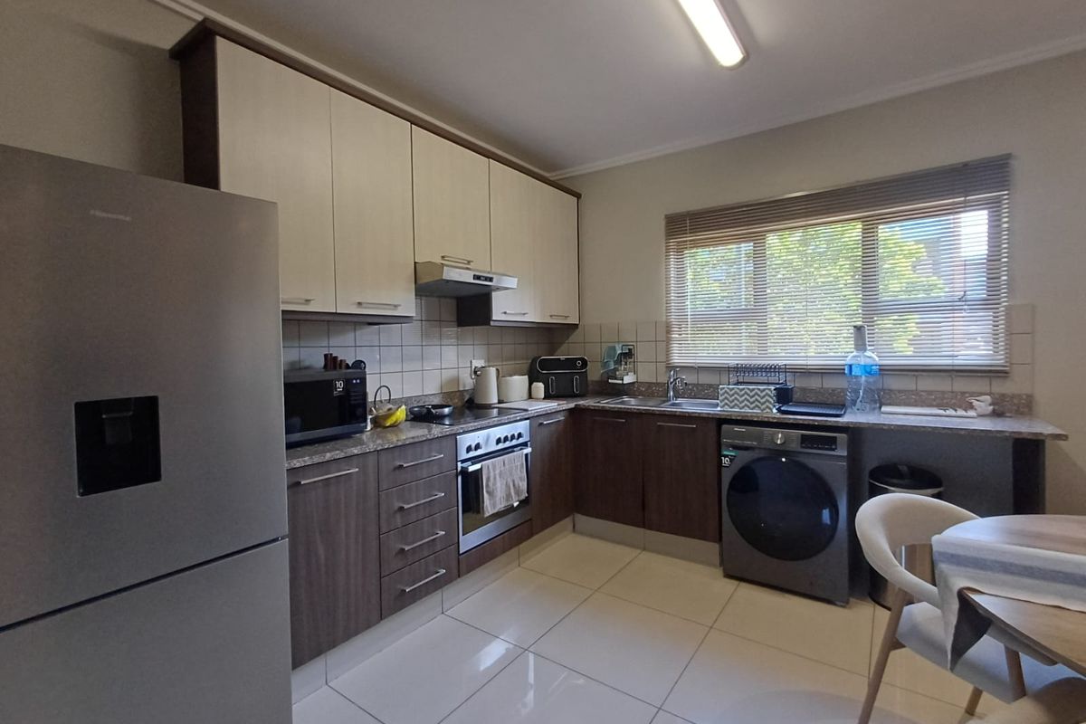 A functional kitchen featuring two-tone cabinetry, tiled backsplash, integrated oven with extractor fan, and tiled flooring, offering a clean and practical workspace.