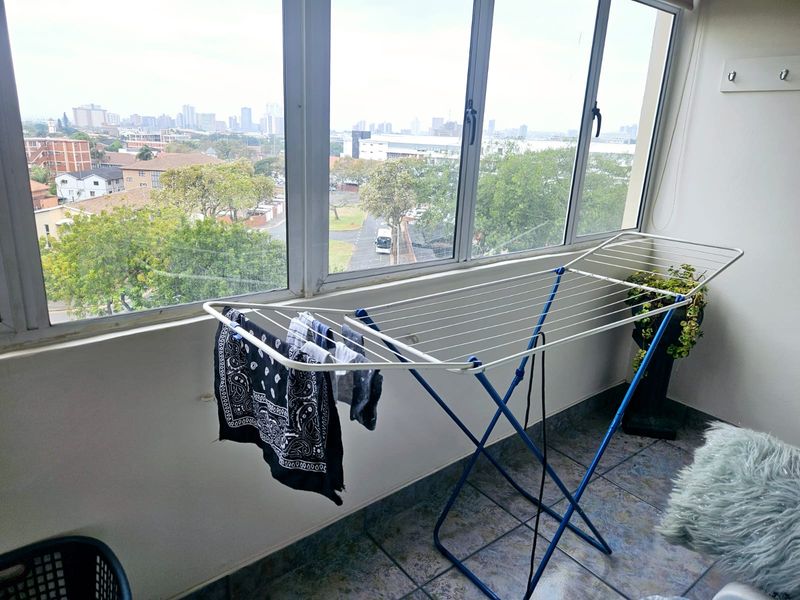 A functional balcony space featuring tiled flooring and large windows offering an expansive urban view, suitable for outdoor relaxation or utility use.