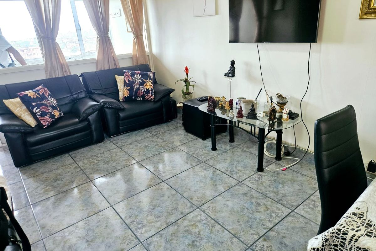 A living room featuring tiled flooring and a wall-mounted television, offering a functional space with neutral wall finishes.