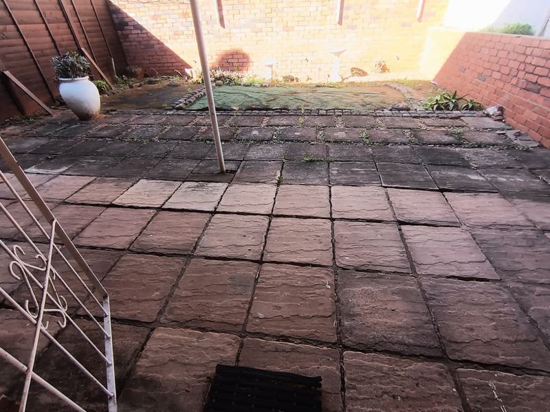 A private rear courtyard featuring paved flooring and brick boundary walls, offering a blank canvas for outdoor landscaping and improvement.