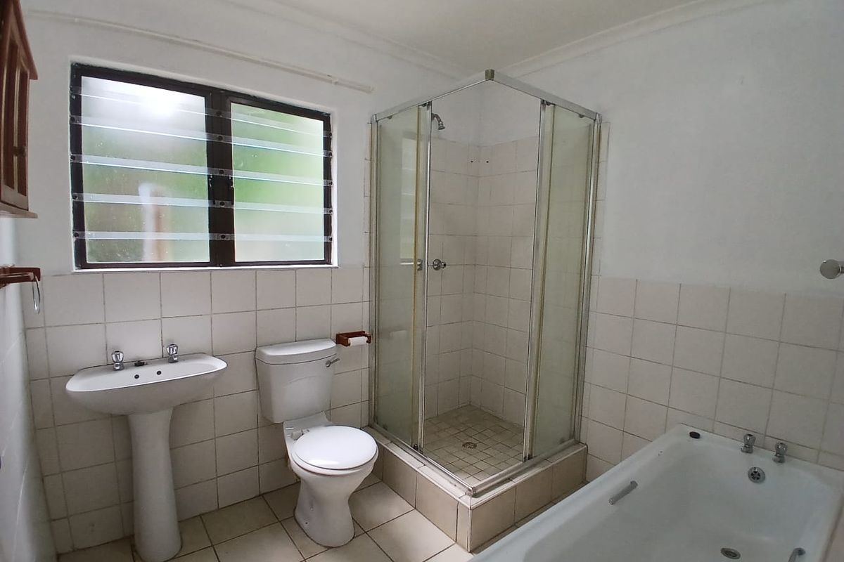 A functional bathroom featuring a pedestal basin, toilet, separate shower enclosure, and a bathtub with tiled finishes throughout.