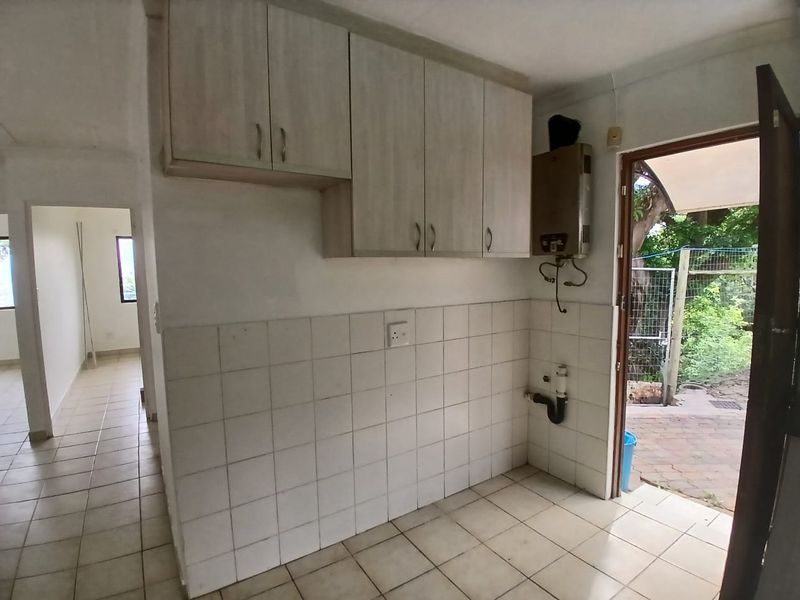A functional laundry area featuring built-in cabinetry, tiled splashbacks, and direct access to the exterior, providing a practical utility space for the home.
