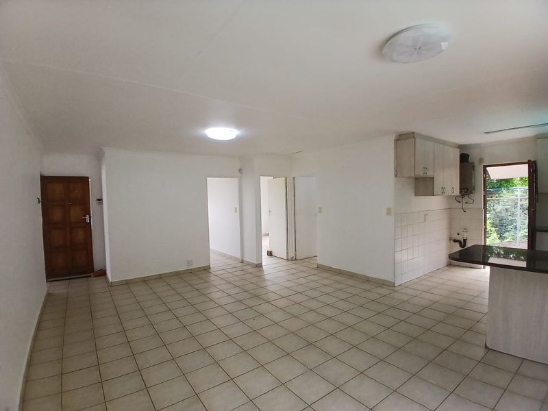 Spacious open-plan living and kitchen area featuring tiled flooring, built-in cabinetry with granite countertops, and direct access to the exterior.