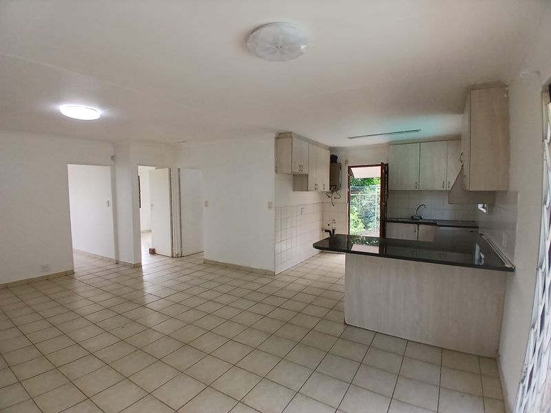 Open plan living and kitchen area featuring tiled flooring, built-in cabinetry with granite countertops, and direct access to an outdoor space.