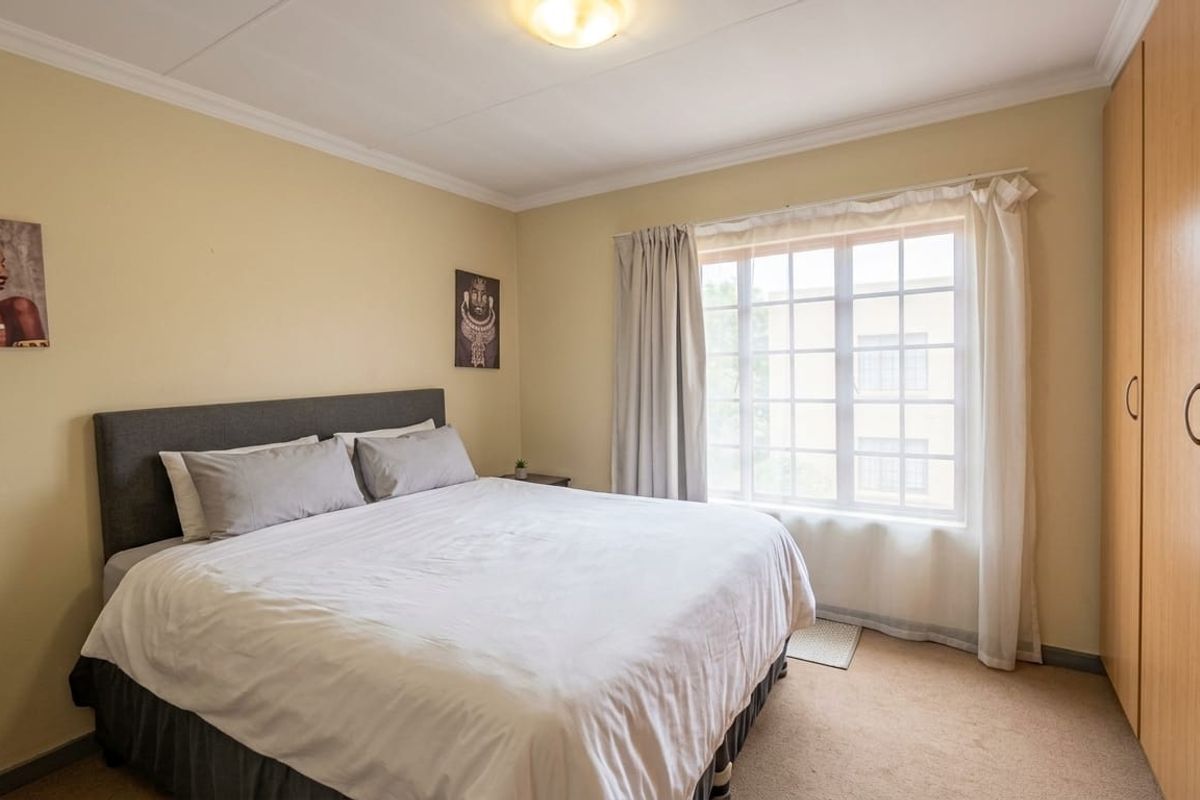 A well-proportioned bedroom featuring neutral walls, carpeted flooring, and ample built-in cupboard storage space.