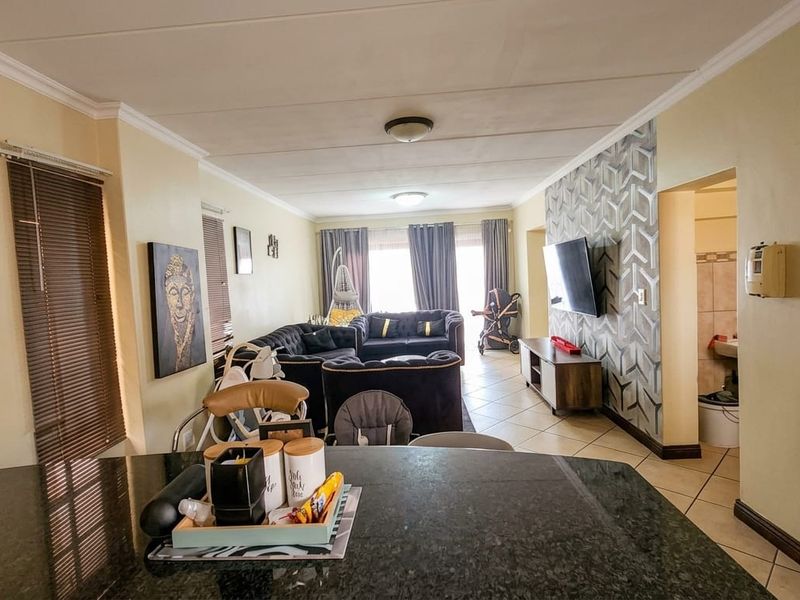 Open-plan living area featuring tiled flooring, a granite kitchen countertop, and a decorative feature wall, providing a functional and connected living space.