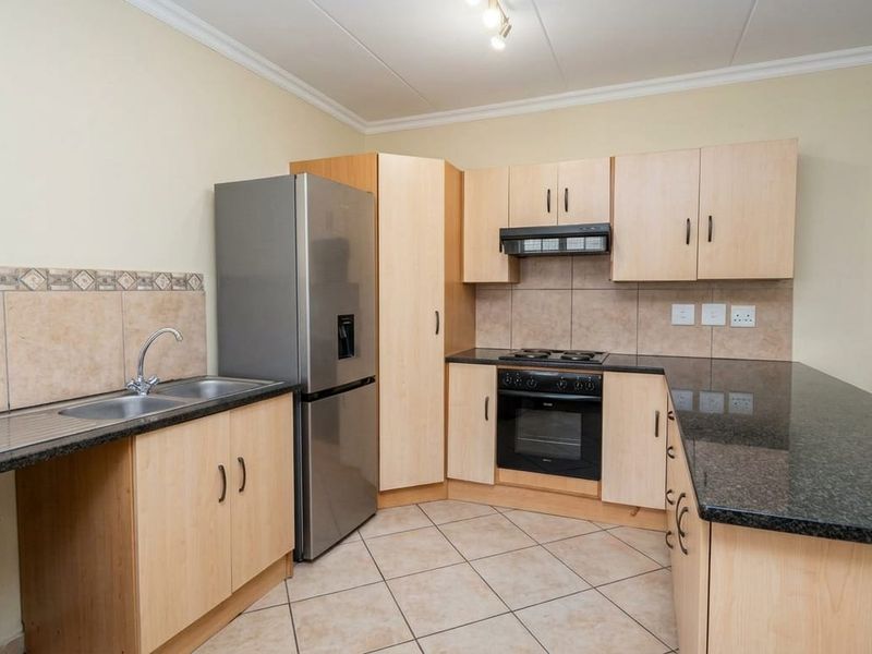 Functional kitchen featuring light wood cabinetry, granite countertops, a double sink, and built-in cooking appliances with a tiled backsplash.