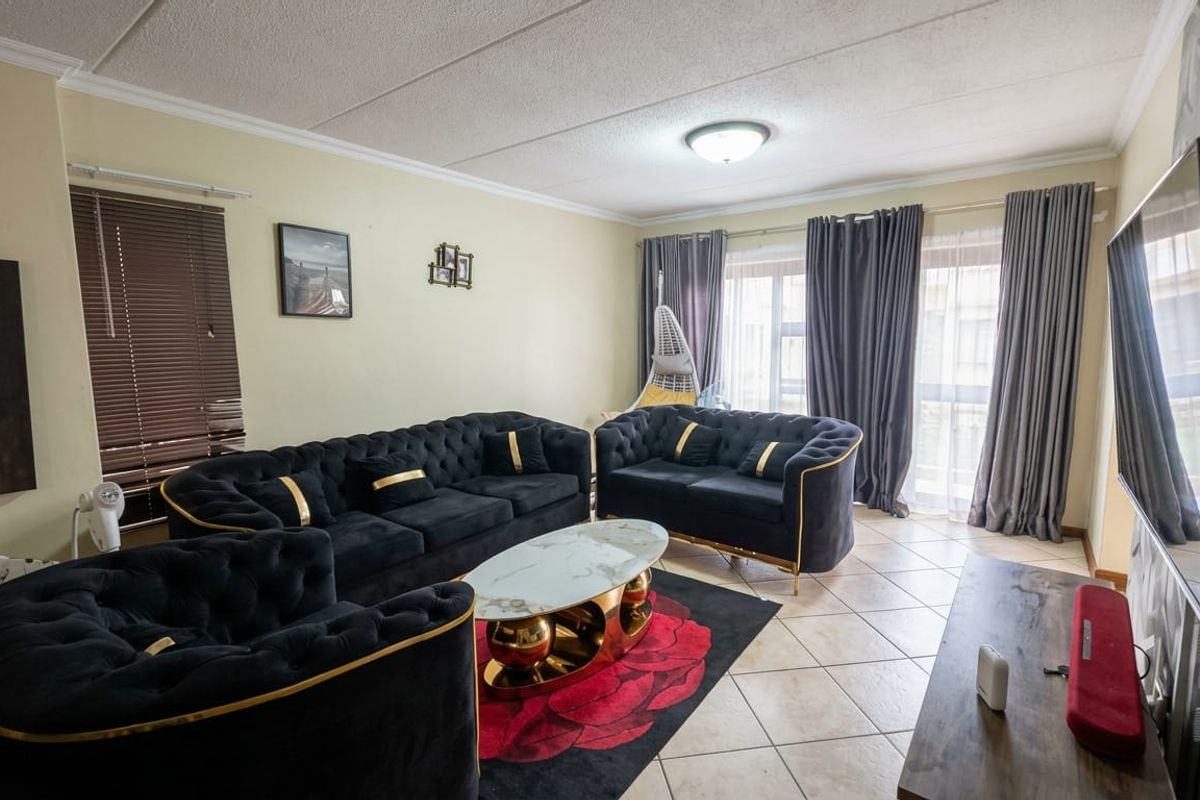 A spacious living room featuring tiled flooring, coved ceilings, and a sliding glass door providing access to the exterior.